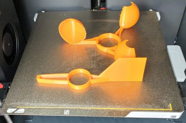 Anemometer parts freshly printed in orange PETG on a textured plate
